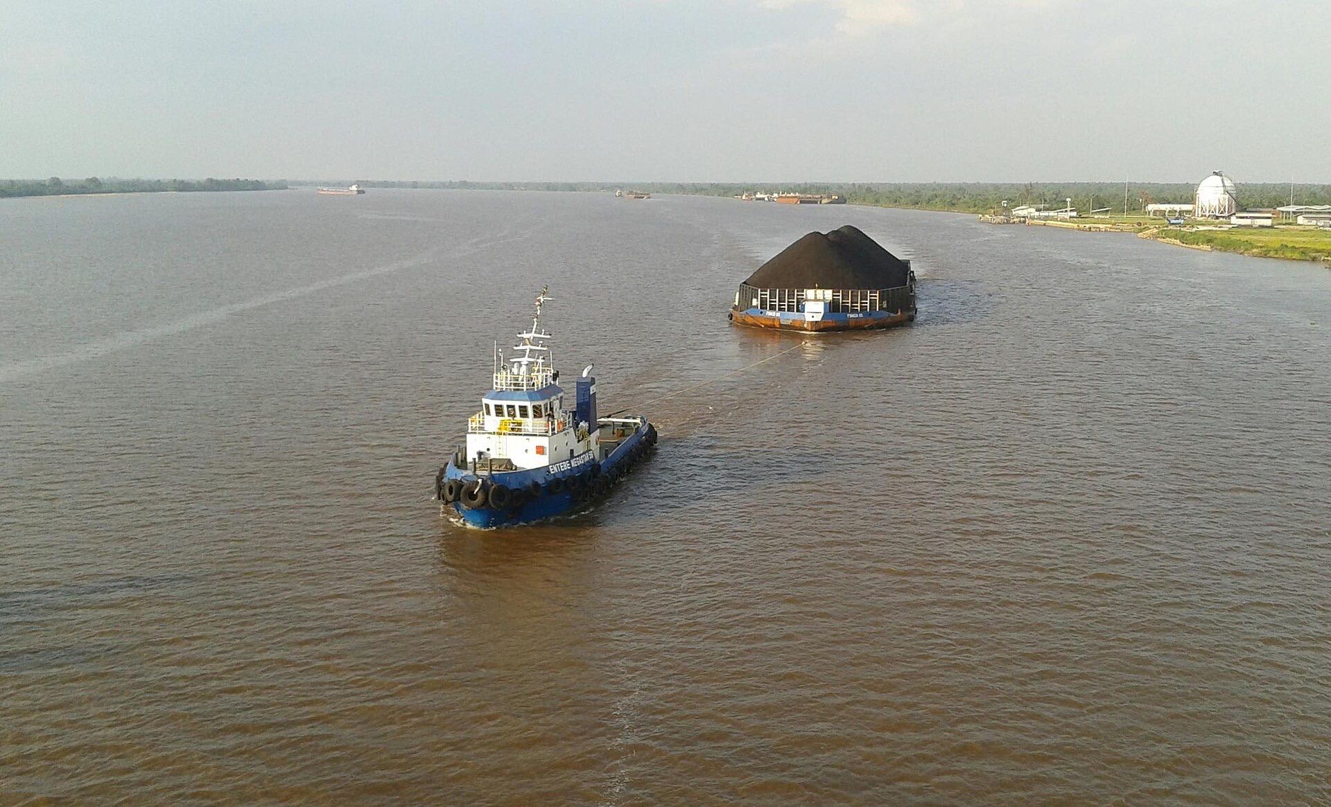 Tug boat towing a coal barge on a river